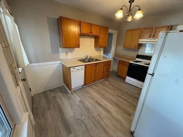 a kitchen with stainless steel appliances granite countertop a refrigerator a sink dishwasher a stove and white countertops with wooden floor