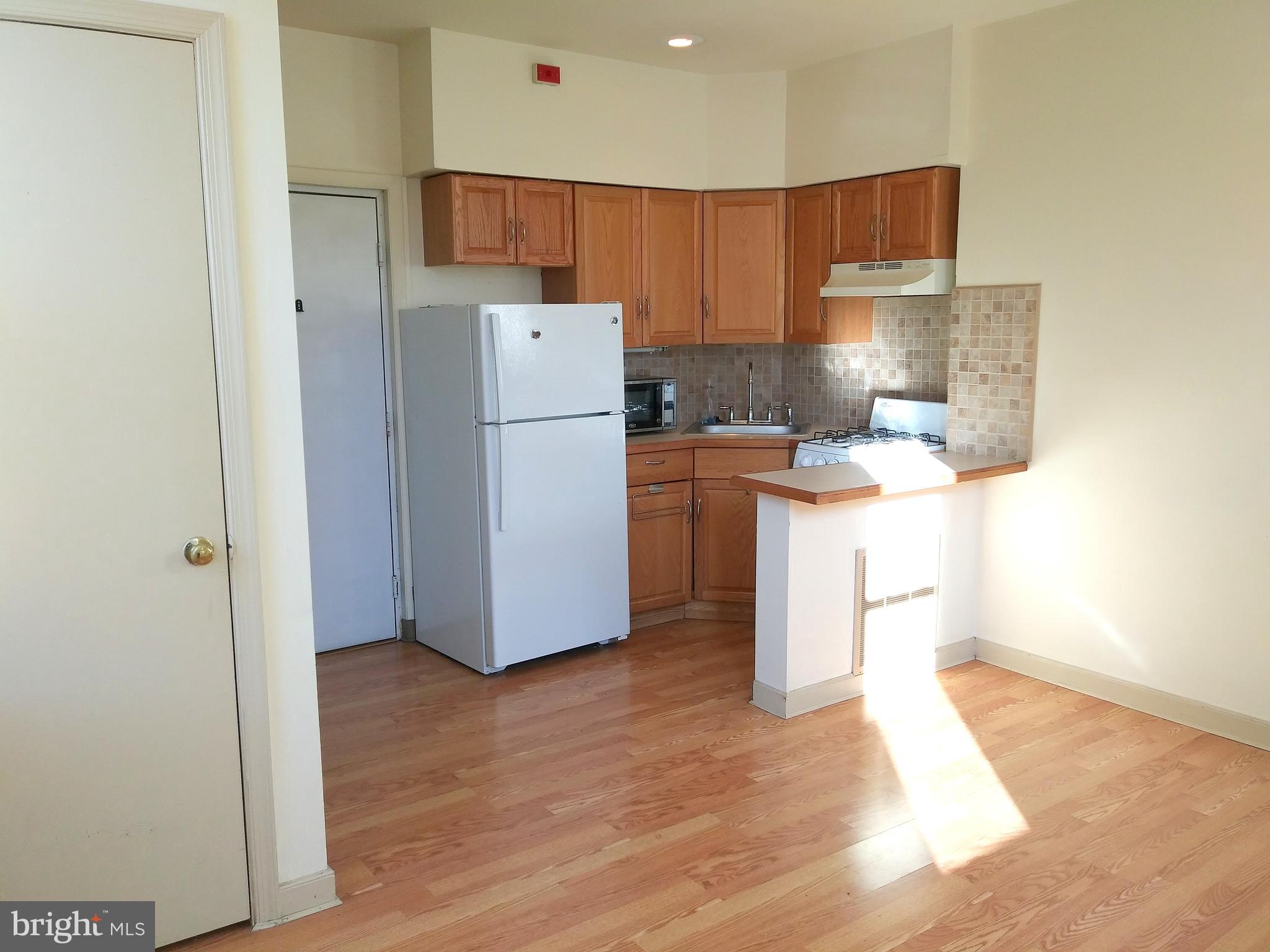 715 South 23rd Street, Unit 1F Philadelphia, PA 19146 - Photo 2 of 12 a kitchen with a refrigerator a stove top oven a sink and cabinets