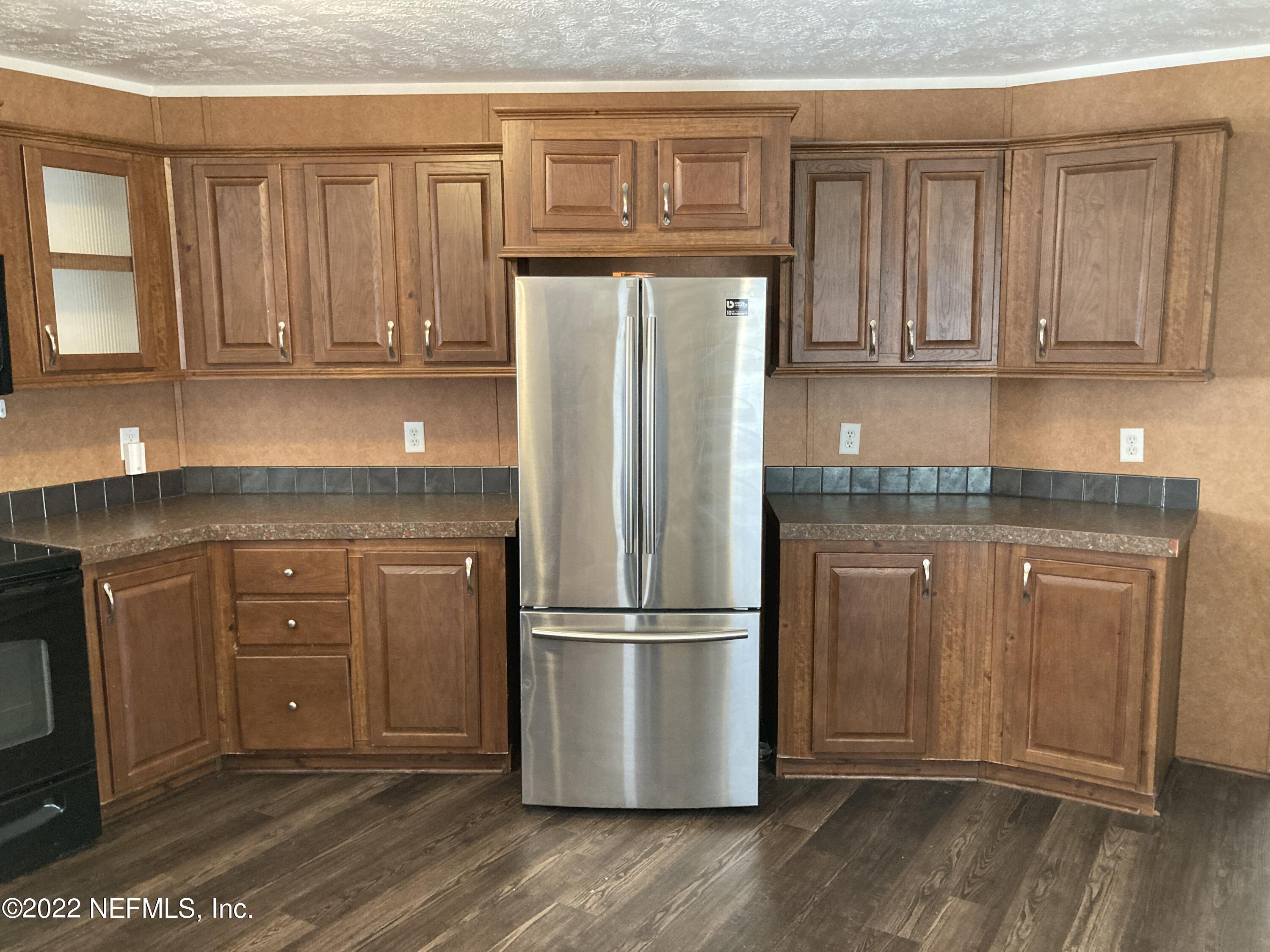 1352 Long Bay Road Middleburg, FL 32068 - Photo 3 of 13 a kitchen with granite countertop wooden cabinets and stainless steel appliances