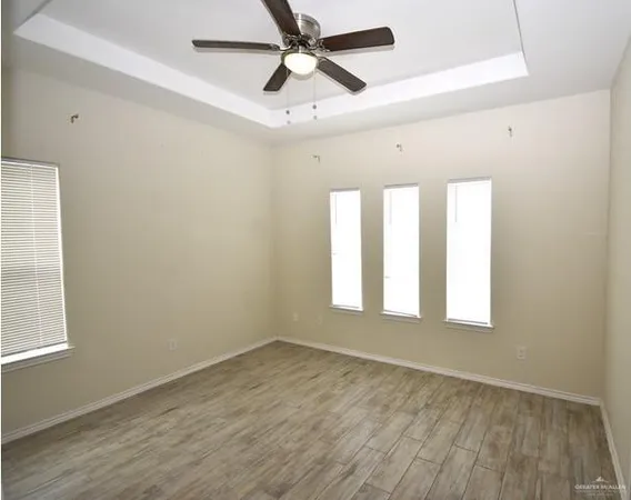 a view of empty room with wooden floor and fan