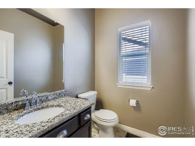 a bathroom with a granite countertop sink toilet and mirror