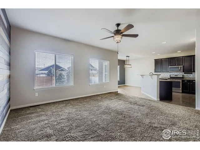 a view of kitchen and empty room with wooden floor