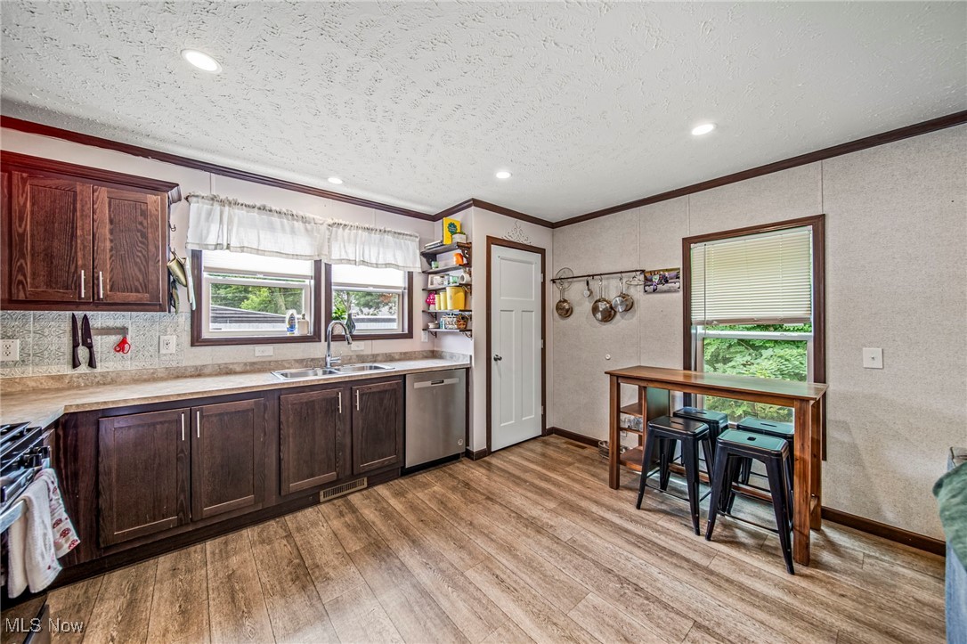 202 West Main Road, Unit LOT 13 Conneaut, OH 44030 - Photo 10 of 23 Kitchen with ornamental molding, light wood finished floors, appliances with stainless steel finishes, light countertops, and dark brown cabinets