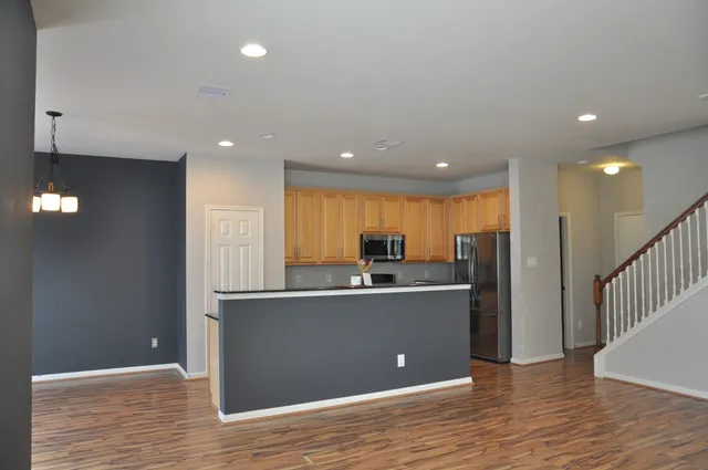 a view of a kitchen with kitchen island a sink wooden floor and a refrigerator
