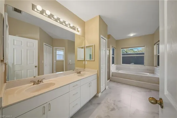 a spacious bathroom with a double vanity sink a large mirror and a bathtub