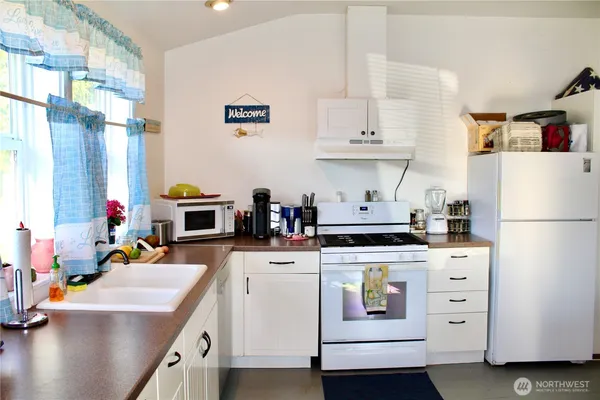 a kitchen with white cabinets and appliances