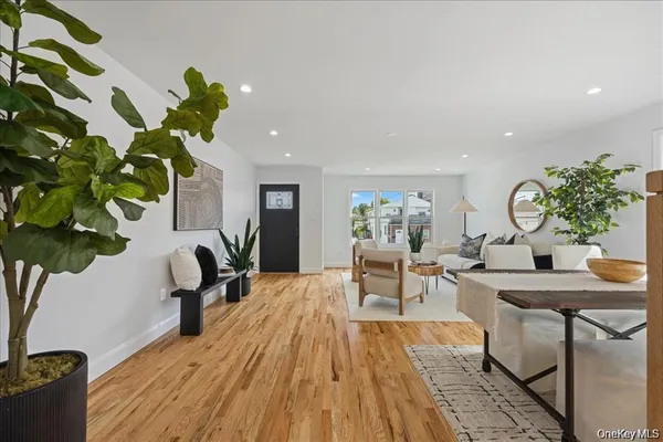 a living room with furniture a potted plant and open kitchen view