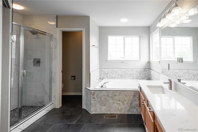 a bathroom with a granite countertop tub shower and sink