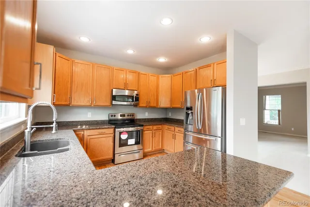 a kitchen with stainless steel appliances granite countertop a refrigerator sink and stove