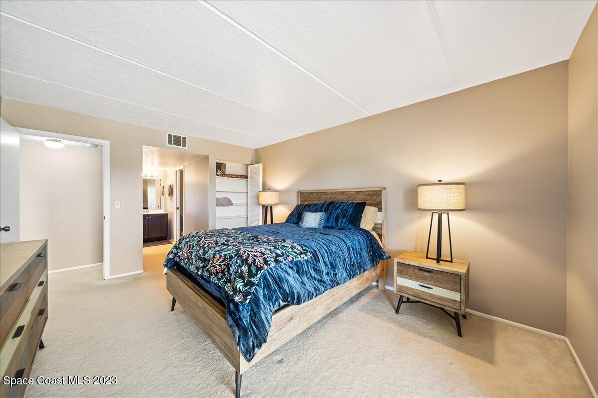 2775 North Wickham Road, Unit 204 Melbourne, FL 32935 - Photo 12 of 24 a bedroom with a bed and a lamp on table