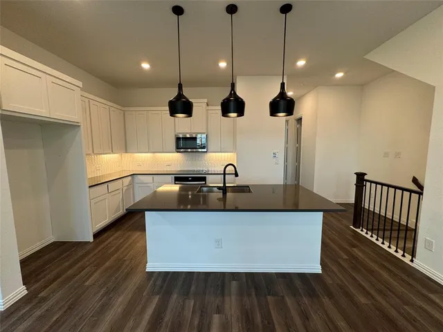 a large kitchen with stainless steel appliances granite countertop a sink a stove and a wooden floors