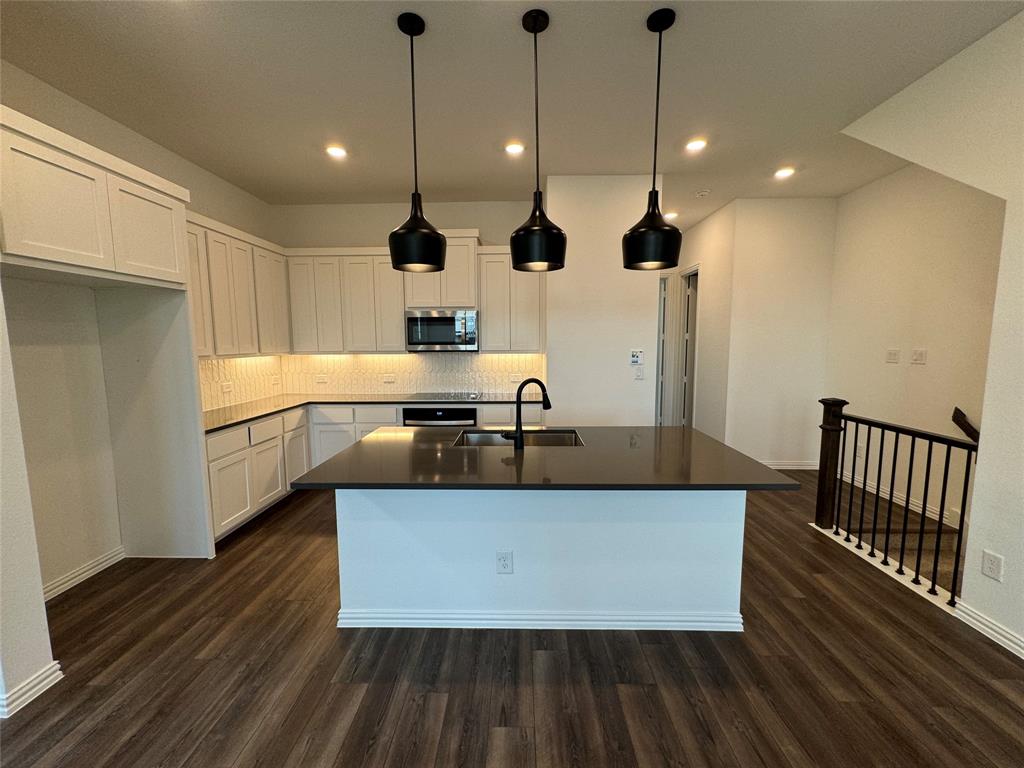 a large kitchen with stainless steel appliances granite countertop a sink a stove and a wooden floors