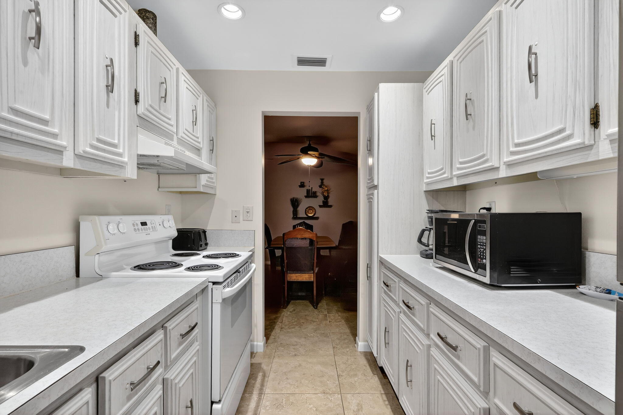 242 West High Point Court, Unit B Delray Beach, FL 33445 - Photo 13 of 36 a kitchen with stainless steel appliances a stove microwave and cabinets