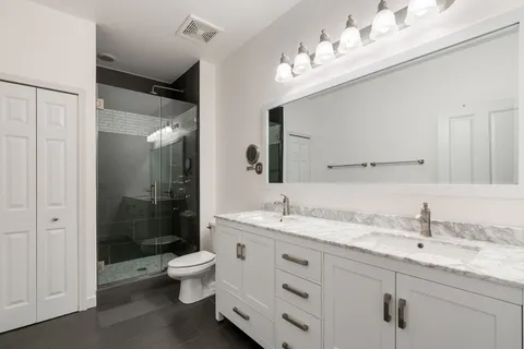 a bathroom with a double vanity sink toilet mirror and shower