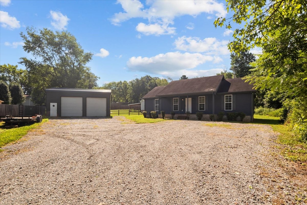 a front view of a house with a yard and a large tree