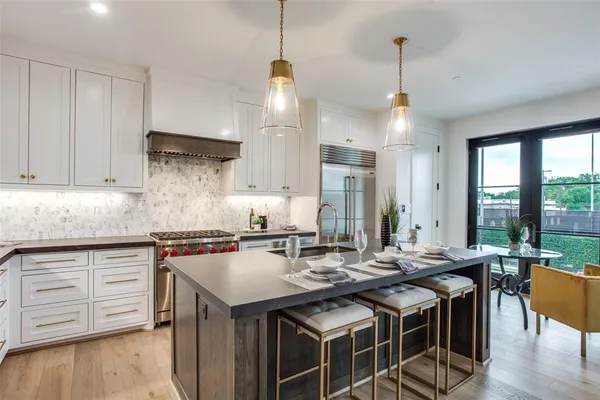 a kitchen with stainless steel appliances granite countertop a sink a stove and a wooden floor