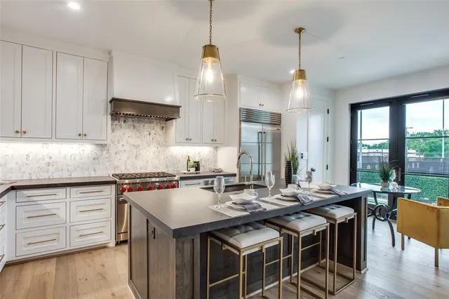 a kitchen with stainless steel appliances granite countertop a sink a stove and a wooden floor