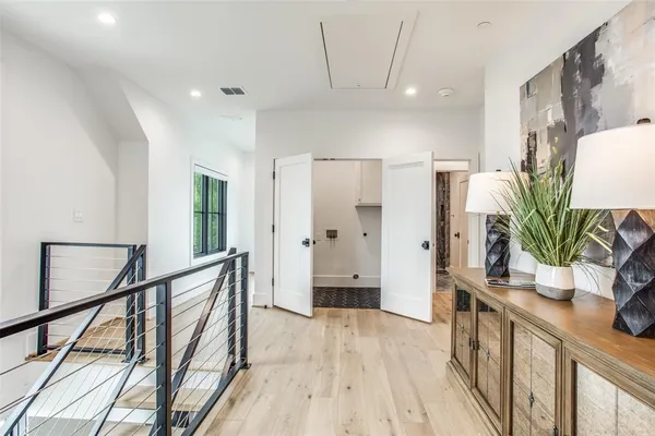 a view of a hallway to a livingroom with wooden floor and furniture