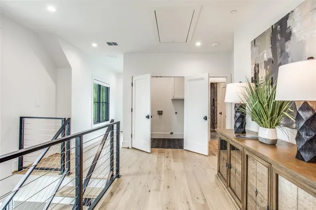 a view of a hallway to a livingroom with wooden floor and furniture