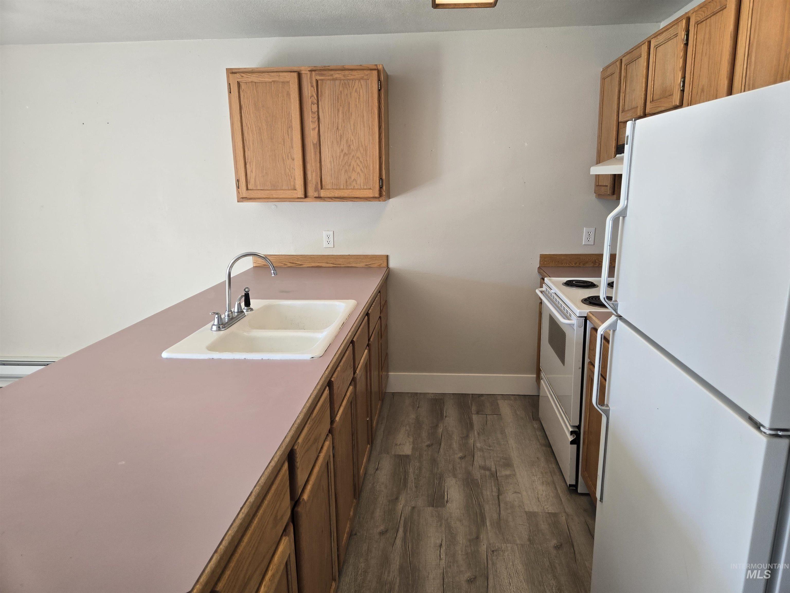 259 Pheasant Road West, Unit 50 Twin Falls, ID 83301 - Photo 11 of 23 Kitchen with white appliances, dark wood finished floors, brown cabinets, and a peninsula
