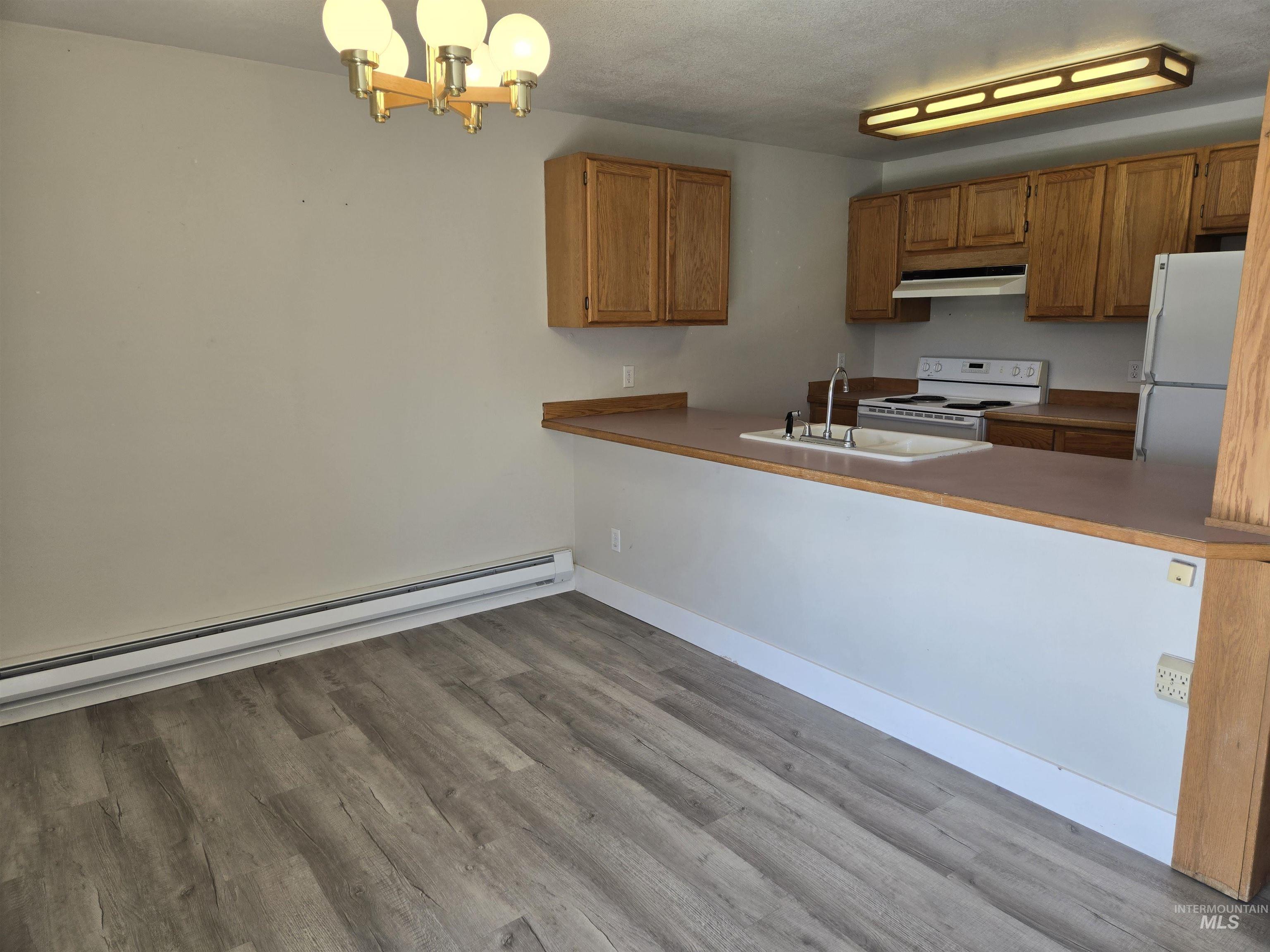 259 Pheasant Road West, Unit 50 Twin Falls, ID 83301 - Photo 15 of 23 Kitchen featuring a baseboard radiator, white appliances, pendant lighting, a chandelier, and light wood-style floors