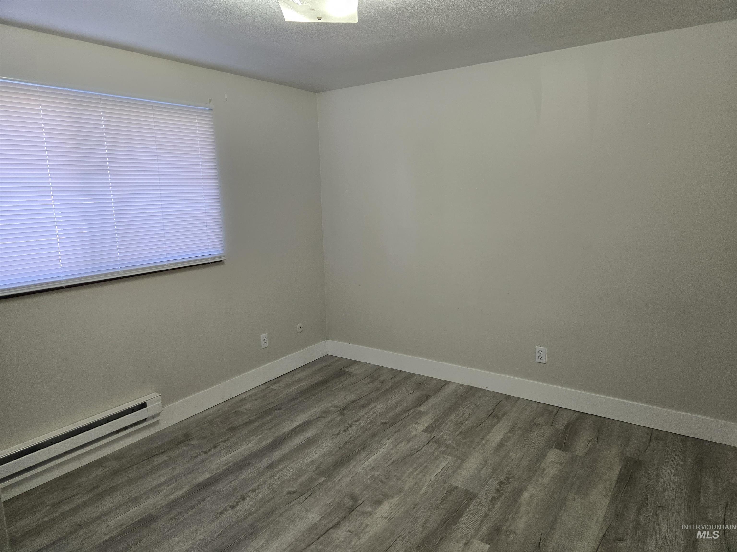 259 Pheasant Road West, Unit 50 Twin Falls, ID 83301 - Photo 17 of 23 Spare room with a baseboard radiator, wood finished floors, and a textured ceiling