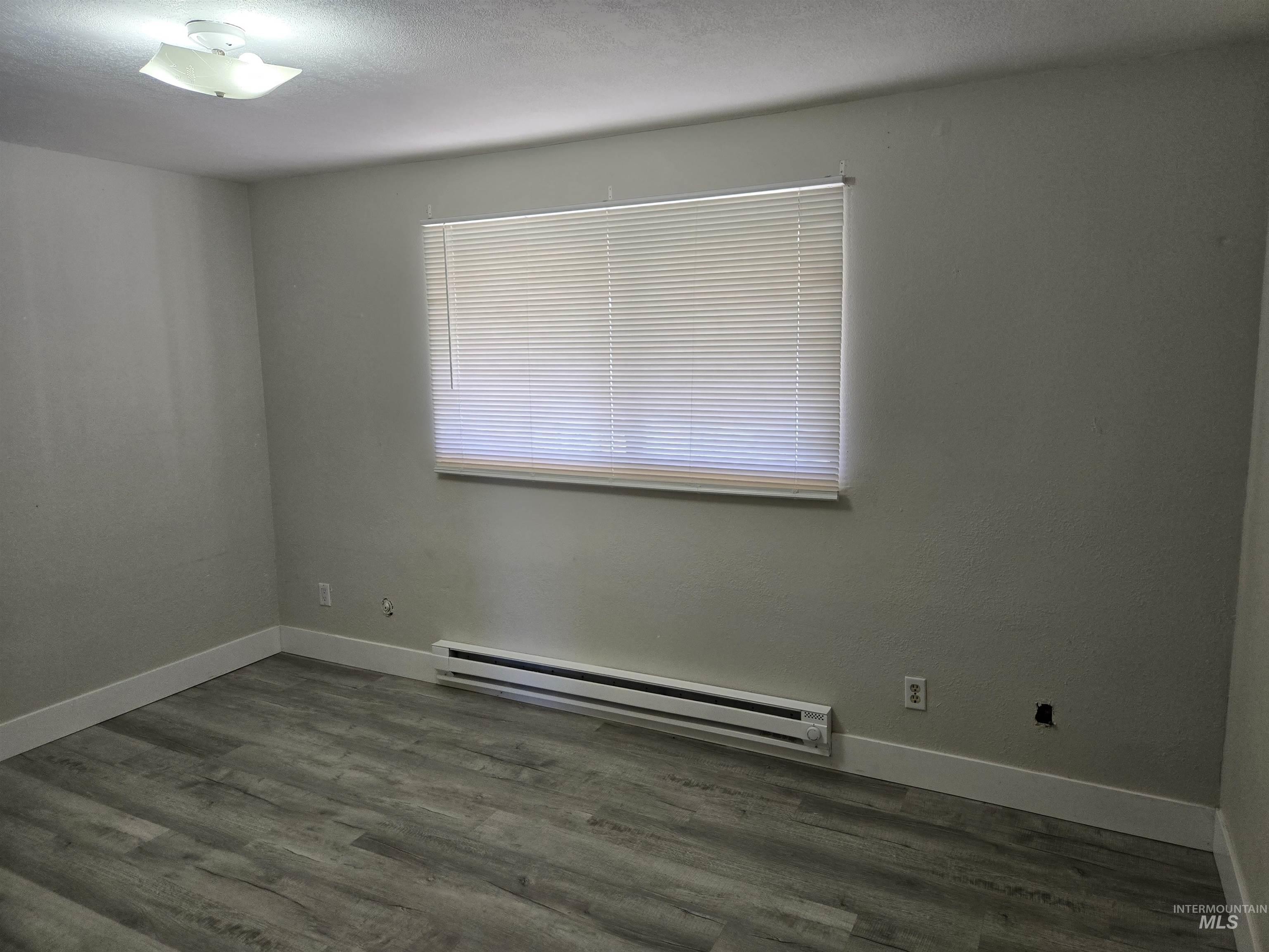 259 Pheasant Road West, Unit 50 Twin Falls, ID 83301 - Photo 21 of 23 Spare room featuring a baseboard heating unit, dark wood-type flooring, and a textured ceiling