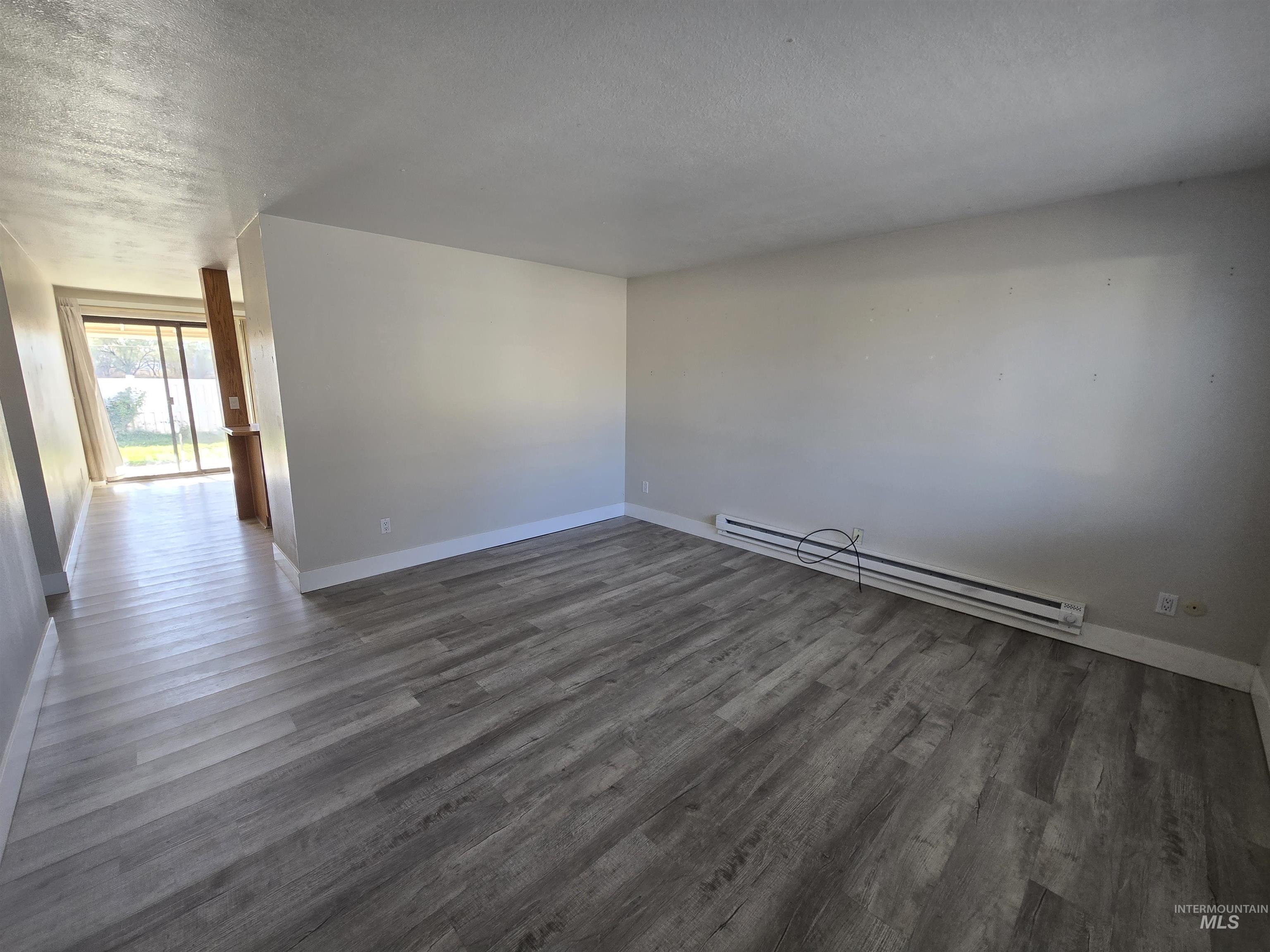 259 Pheasant Road West, Unit 50 Twin Falls, ID 83301 - Photo 6 of 23 Empty room featuring baseboard heating, a textured ceiling, and dark wood finished floors