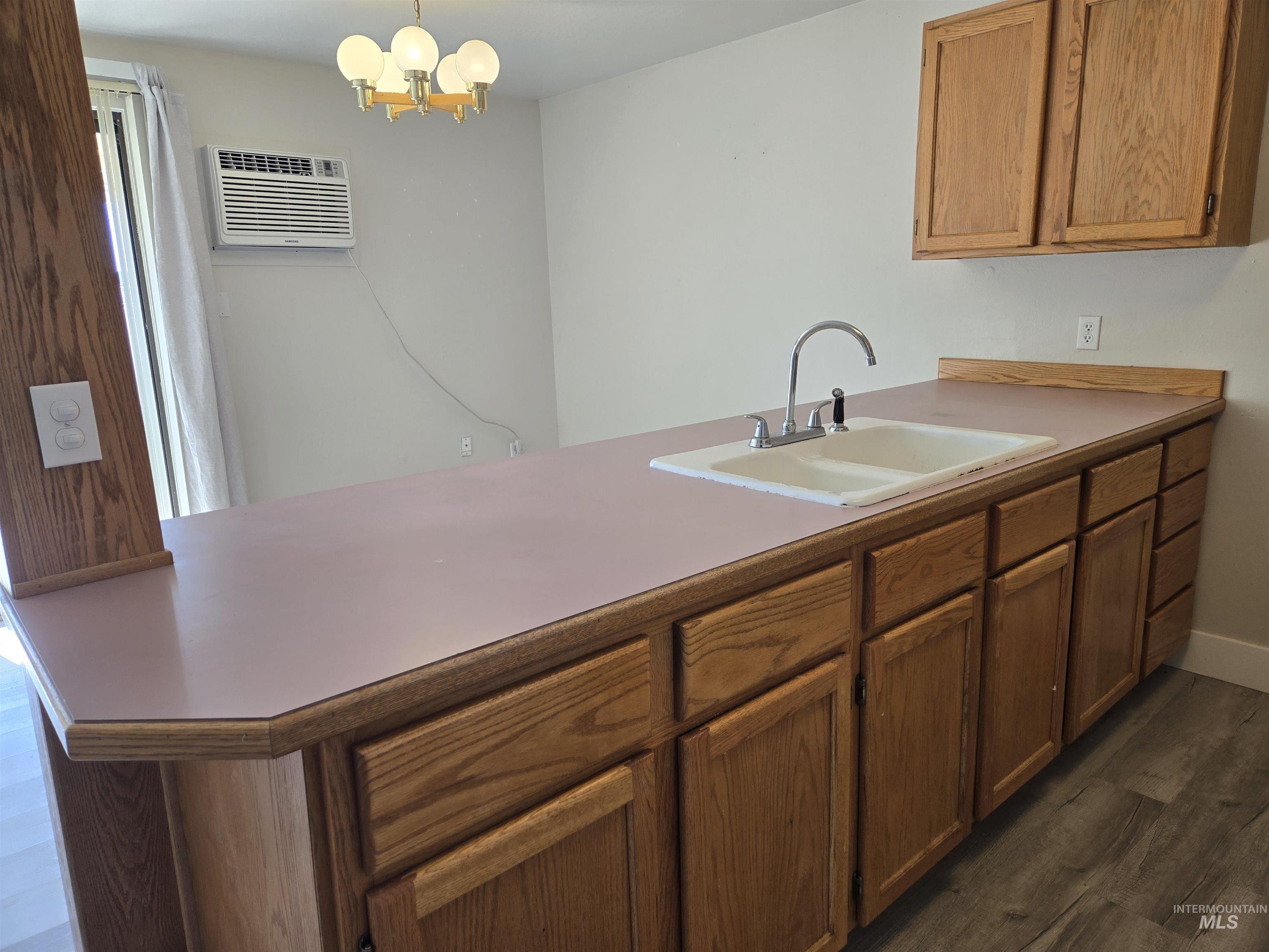 259 Pheasant Road West, Unit 50 Twin Falls, ID 83301 - Photo 10 of 23 Kitchen with pendant lighting, a peninsula, dark wood-type flooring, light countertops, and a chandelier