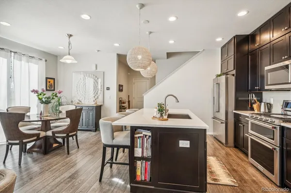 a kitchen with stainless steel appliances granite countertop a sink a stove a refrigerator cabinets and living room view