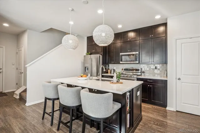 a kitchen with stainless steel appliances granite countertop a sink a stove a refrigerator with a dining table and chairs