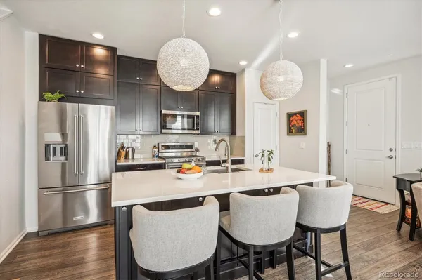 a kitchen with stainless steel appliances granite countertop a sink a microwave a refrigerator and chairs