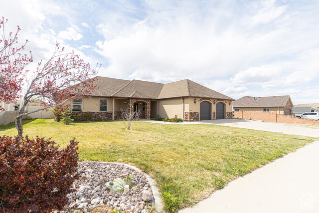 5095 North Rdg Vw Circle Cedar City, UT 84721 - Photo 1 of 1 View of front facade with fence, an attached garage, driveway, stone siding, and a front yard