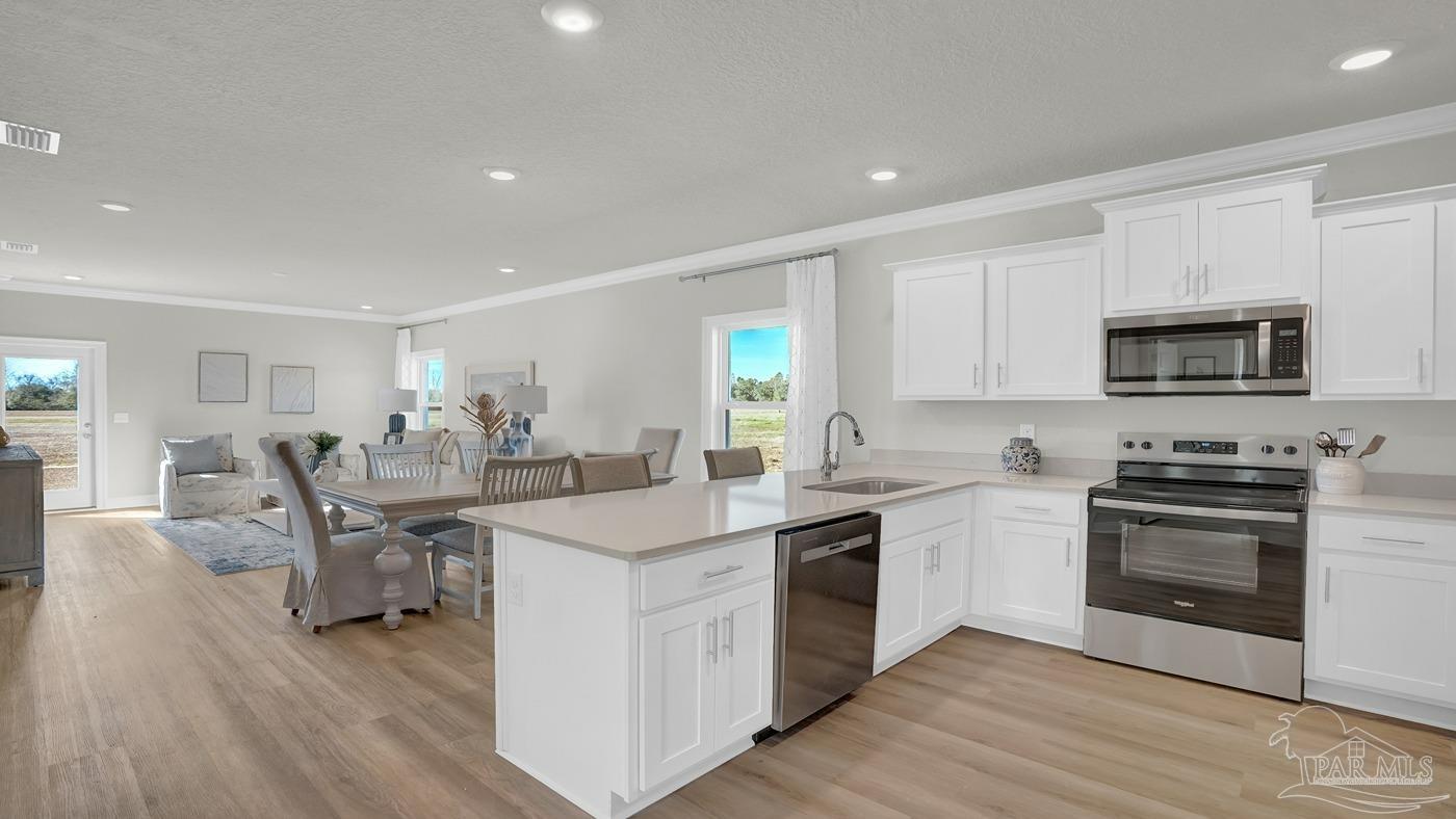 24 Spoonbill Street Cantonment, FL 32533 - Photo 17 of 30 a kitchen with appliances a sink and chairs