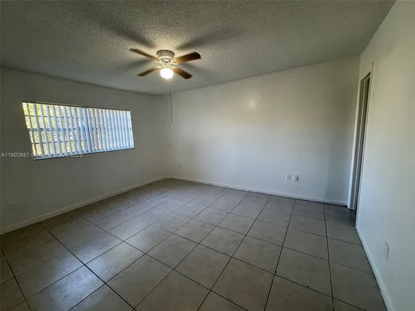 an empty room with windows and fan