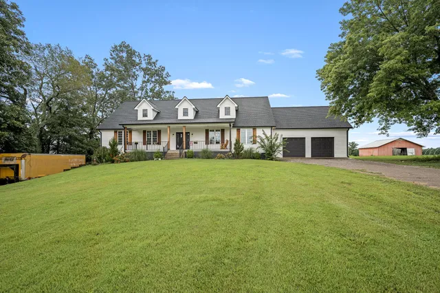 a view of a house next to a big yard and large trees