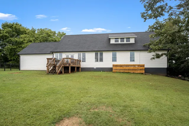 a view of a house next to a big yard and large trees
