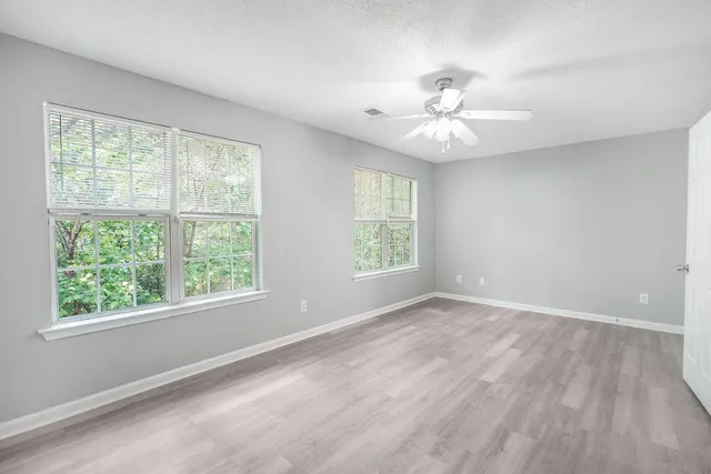 an empty room with windows and ceiling fan