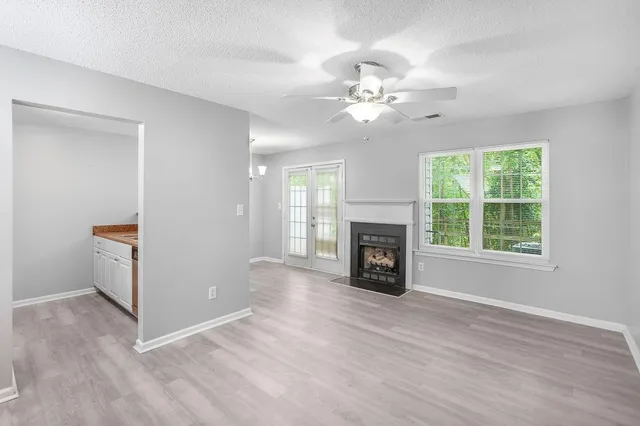 an empty room with windows fireplace and a ceiling fan