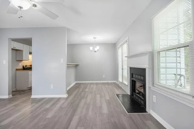 an empty room with wooden floor a fireplace and windows