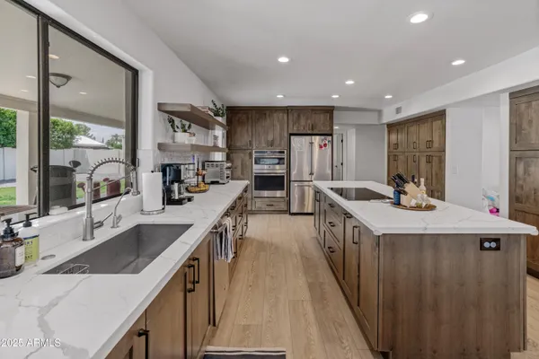 a kitchen with stainless steel appliances kitchen island granite countertop a dining table chairs sink and cabinets