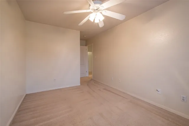 an empty room with a chandelier fan and closet area