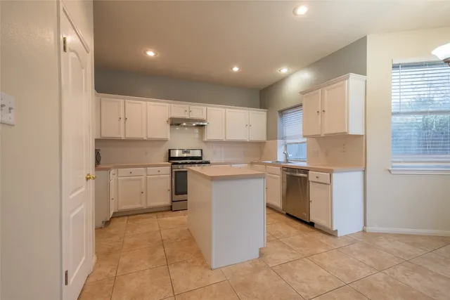 a kitchen with a refrigerator and white cabinets
