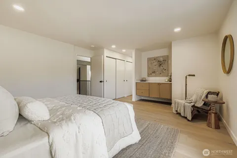 a spacious bedroom with a bed and a view of kitchen