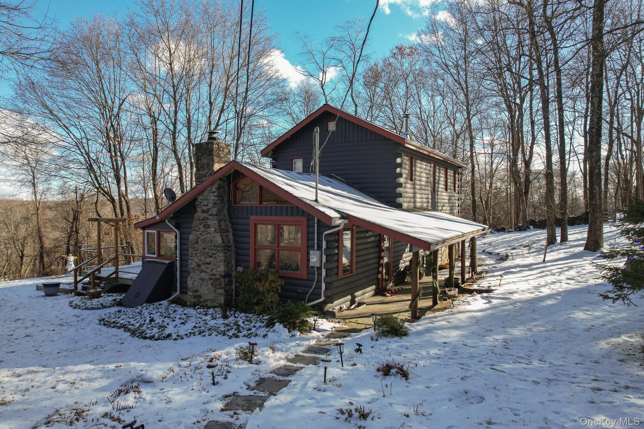 View of front of home featuring log siding, a chimney, and a porch
