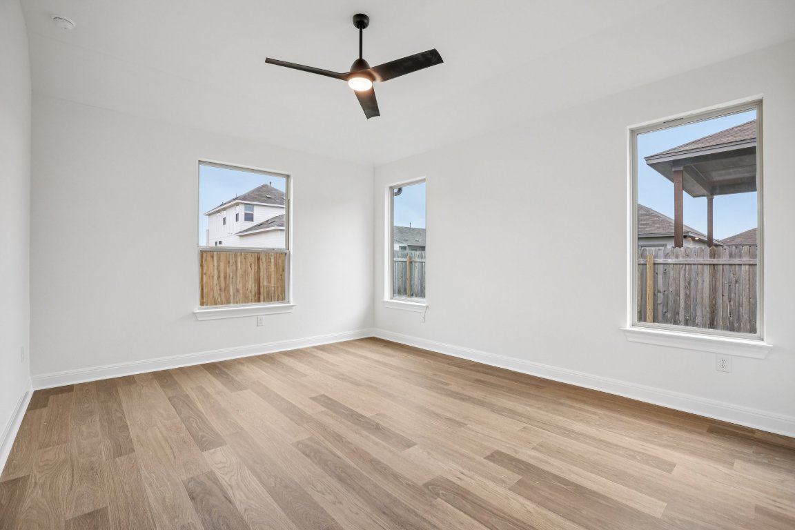 581 Treadwell Lane Kyle, TX 78640 - Photo 18 of 27 an empty room with wooden floor chandelier and windows