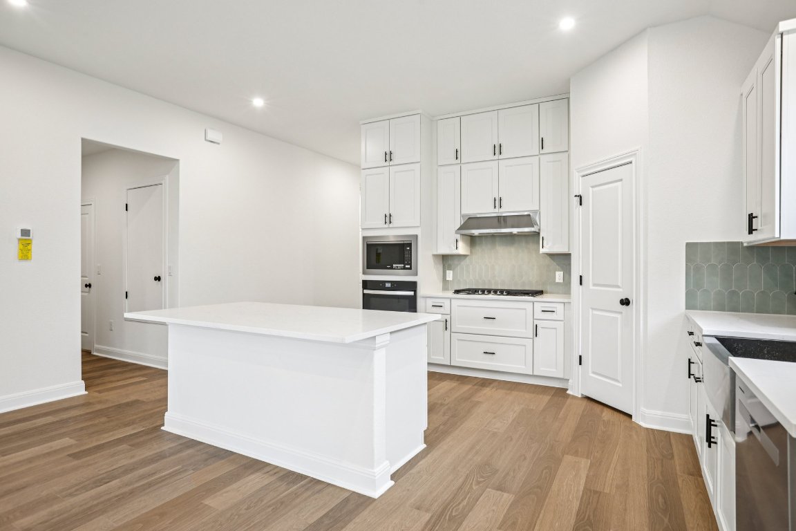 581 Treadwell Lane Kyle, TX 78640 - Photo 6 of 27 a kitchen with white cabinets and stainless steel appliances