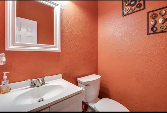 a white toilet sitting next to a white sink and a mirror