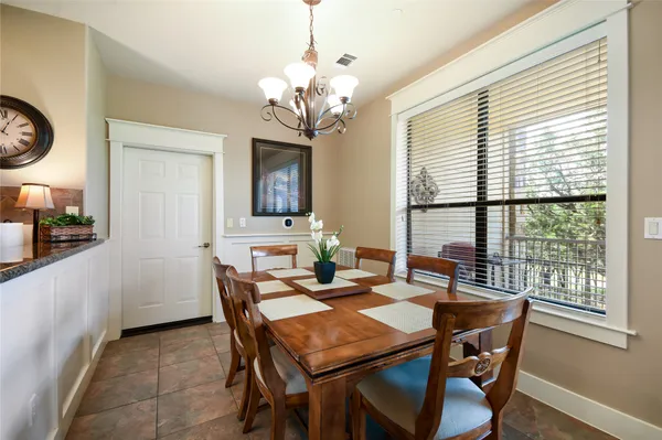 a dining room with wooden floor a chandelier a wooden table and chairs