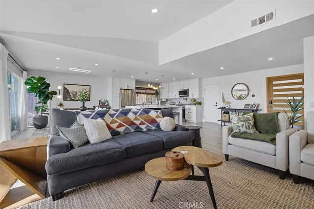 a living room with furniture kitchen view and a chandelier